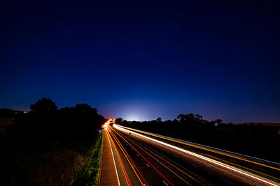 Light trails on road against sky at night