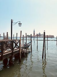 Wooden posts in canal against clear sky