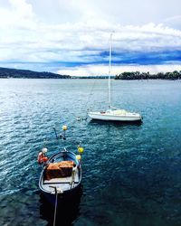 Sailboats moored on sea against sky