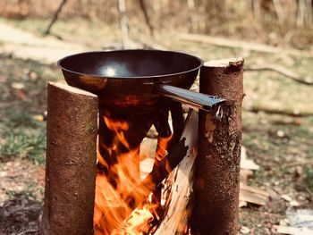 Close-up of cooking pan on firewood at campsite in forest