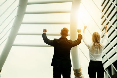 Rear view of cheerful business colleagues standing in modern office