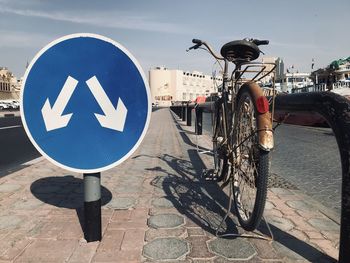 Bicycle sign on road against sky