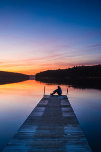 Pier over lake against sky during sunset