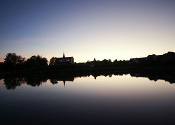 Reflection of built structure in calm lake at sunset