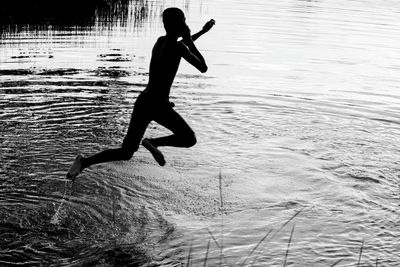 Silhouette boy jumping in river