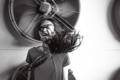 Young woman standing by fans