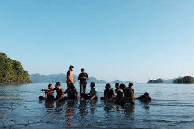 People on sea against clear sky