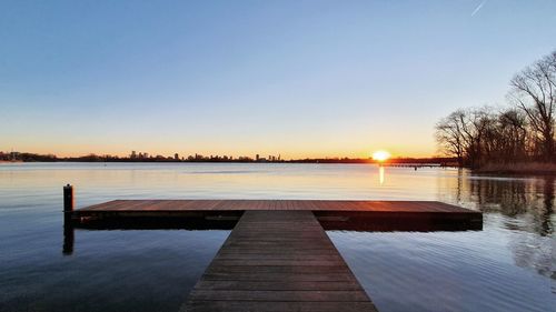 Pier over lake against clear sky during sunset