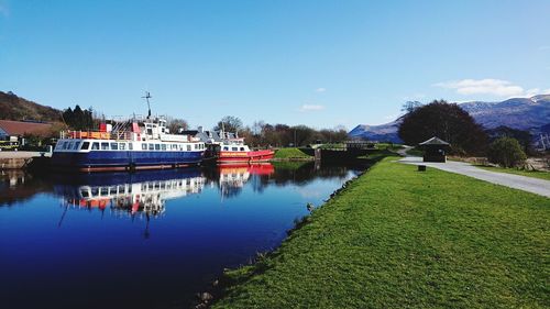 Boats moored in lake against blue sky