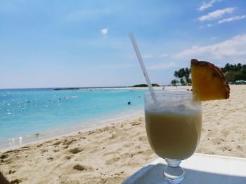 Close-up of drink on beach against sky