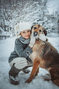 Portrait of boy with dog on snow