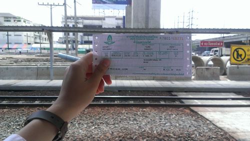 Close-up of hand holding train at railroad station