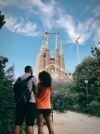 Rear view of couple standing by trees against sky