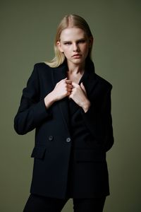 Portrait of young man standing against gray background