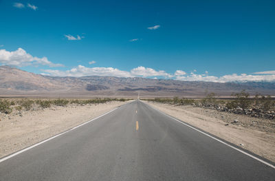 Road by desert against blue sky