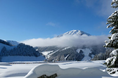 Scenic view of snow covered mountains against blue sky
