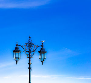 Low angle view of telephone pole against clear blue sky