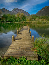 Pier over calm lake against mountain range