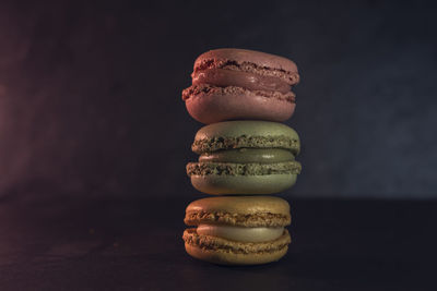 Front view of three macarons of different colors on dark background