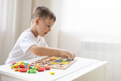 Side view of boy using calculator while sitting at home