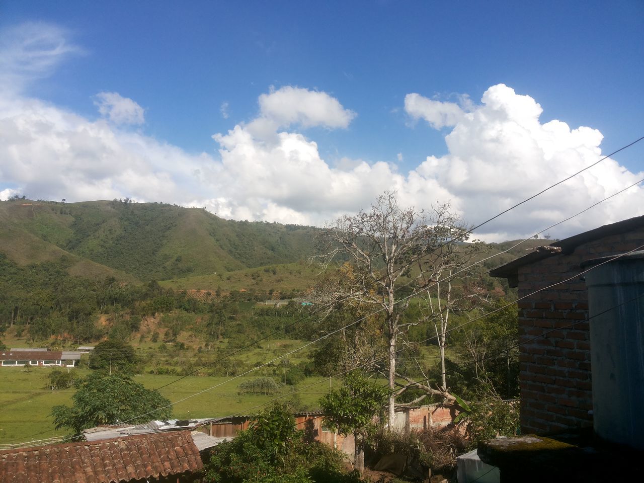 building exterior, architecture, built structure, sky, tree, house, mountain, cloud - sky, residential structure, residential building, cloud, blue, town, day, landscape, nature, outdoors, residential district, beauty in nature, no people