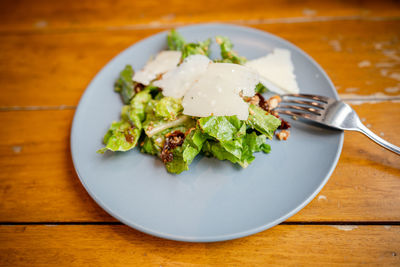 Green vegetable salad with parmesan cheese toppings in a plate.