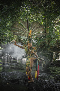 Full length of boy standing on tree trunk the dayak costume