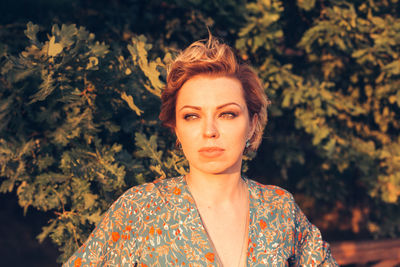 Portrait of young woman standing against blurred background