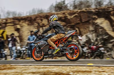 Side view of man riding motorcycle on road against rock formations