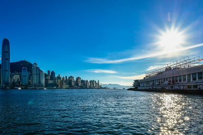 Sea by buildings against blue sky