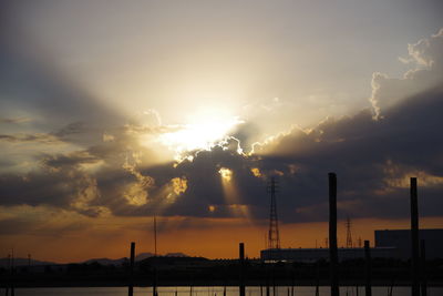 Sunlight streaming through silhouette of city during sunset