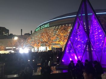 People enjoying illuminated music concert against sky at night