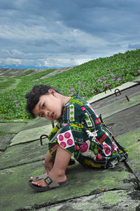 Portrait of girl sitting against sky