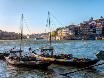 Sailboats moored on sea against buildings in city