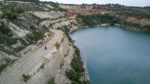 A motorbike driving near a cliff above a lake