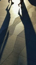 Low section of people with shadow on floor