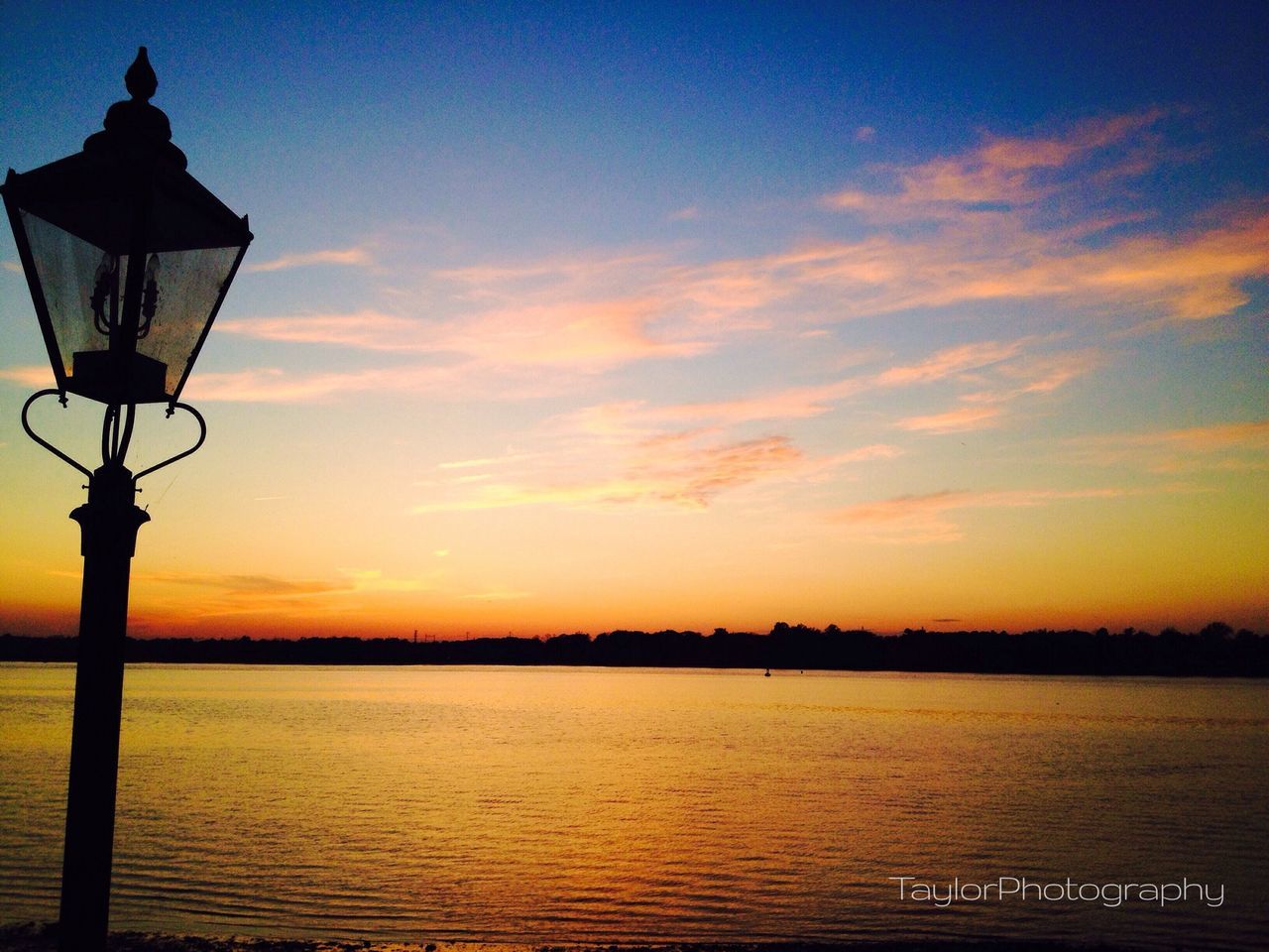 sunset, silhouette, water, sky, orange color, sea, scenics, tranquility, tranquil scene, beauty in nature, nature, idyllic, built structure, lighting equipment, waterfront, street light, horizon over water, guidance, architecture, cloud - sky