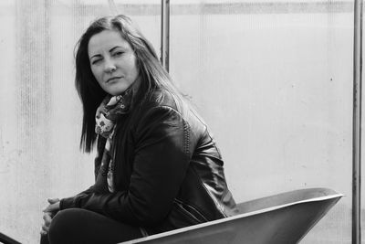 Portrait of young woman sitting against wall