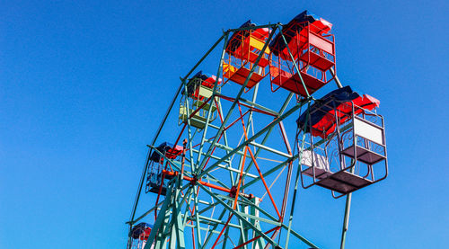 Low angle view of ferris wheel against clear blue sky