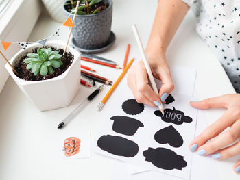 Woman writes boo on decorative black stickers for flower pots. handmade halloween decorations.