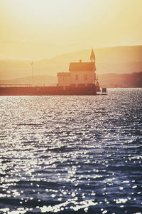 Scenic view of sea by building against sky during sunset