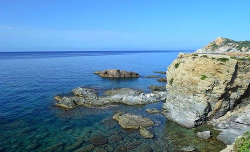 Scenic view of rocks in sea against blue sky