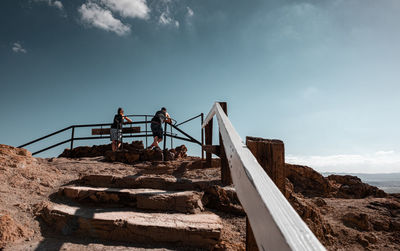 Low angle view of people standing on staircase against sky