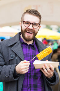 Portrait of smiling man holding ice cream standing outdoors