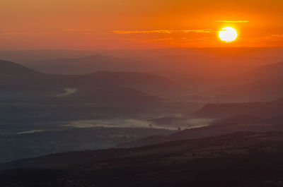 Scenic view of silhouette mountains against orange sky