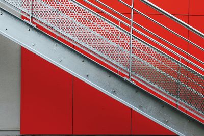 Low angle view of metallic steps by red wall