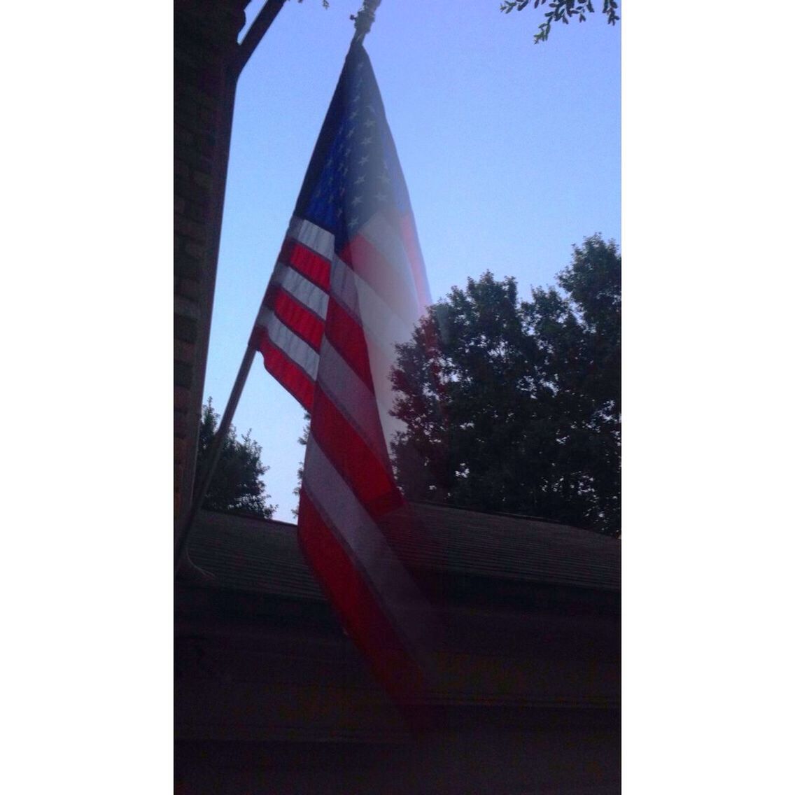 architecture, flag, built structure, patriotism, building exterior, clear sky, american flag, national flag, identity, low angle view, tree, red, day, tower, sky, culture, tall - high, no people, outdoors, city