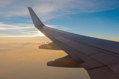 Airplane wing against sky during sunset