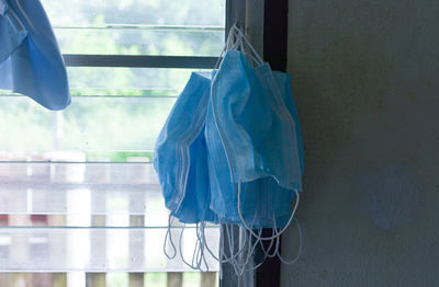 Close-up of protective masks hanging by window