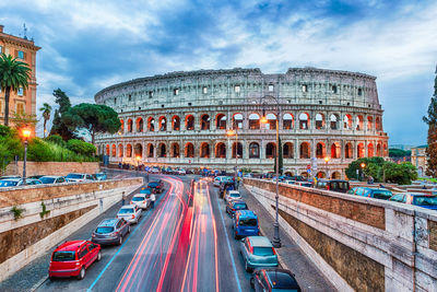 Light trails on road towards coliseum against blue sky